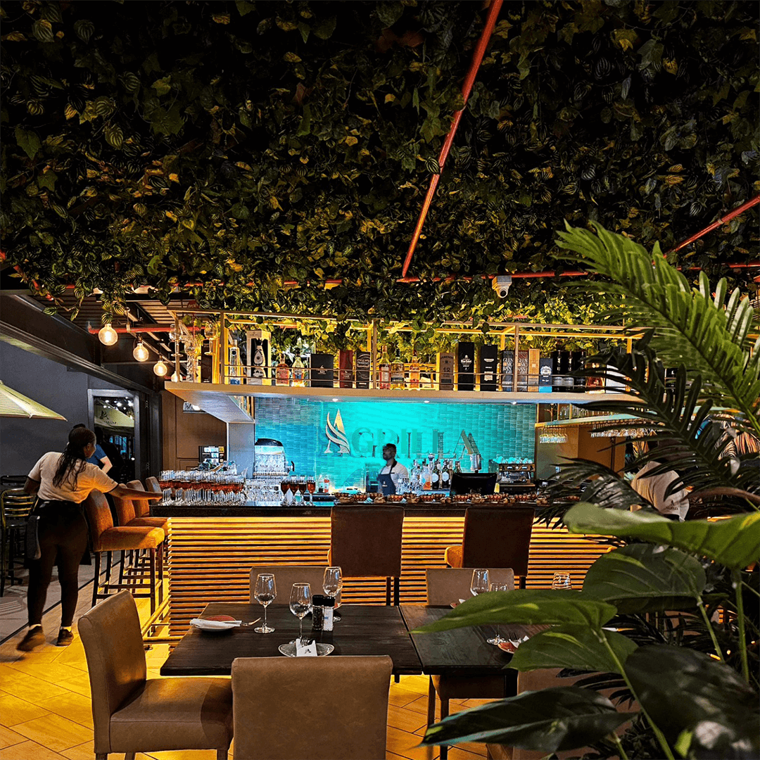 Elegant interior view of Agrilla Meet and Cocktail Bar featuring a lush green ceiling, ambient lighting, and a modern bar area.